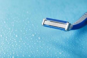 Shaving machine with three blades on a blue background with water drops in close-up photo