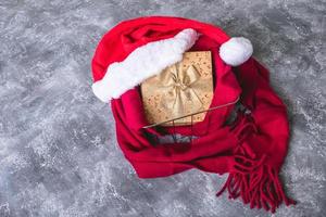 Top view of santa hat with scarf and gift box on gray grunge background. photo