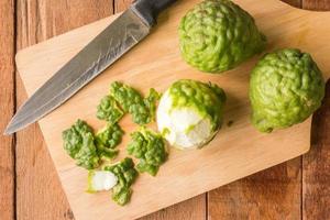 Sliced skin bergamot or kaffir lime with knife on wooden table background. photo