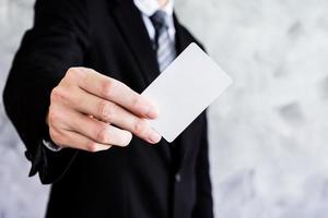 primer plano de un hombre de negocios que sostiene una tarjeta blanca en blanco sobre un fondo grunge. foto