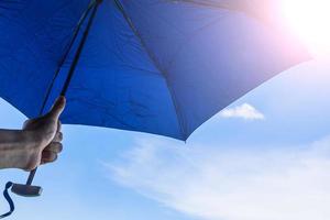 Hand holding umbrella with blue sky and sunlight background photo