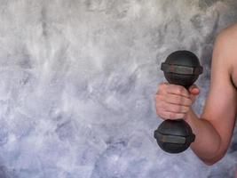 Close up of male hand holding a dumbbell  on grunge background. Free space for text photo