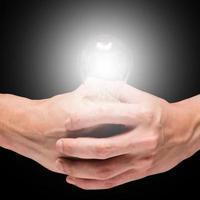Male hands holding light bulb on a black background. photo