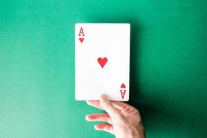 Hand holding a playing card on green background. photo