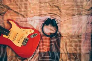 vista superior de guitarra eléctrica y auriculares en el dormitorio, filtro de grano de películas. foto