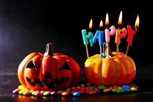 Halloween pumpkin with candies and candlelight on a black background. photo