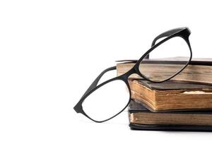 A stack of old books with eyeglasses on a white background. Free space for text photo