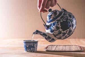 primer plano de la mano masculina vertiendo té de la tetera china foto