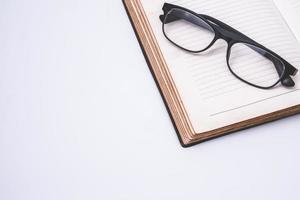 An open notebook with glasses on white background. Free space for text photo