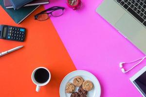 Laptop, office supplies, coffee and cookies on colorful background. Free space for text photo