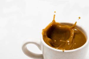 Cup of splashing coffee on white background photo