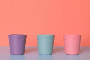 Three color plastic cup on pastel colors background. photo