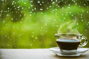 Cup of coffee on the table inside the window, coffee break in the morning with rainy day, relaxing and refreshing concepts. photo