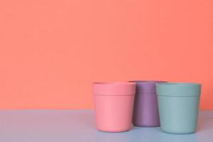 Three color plastic cup on pastel colors background. photo