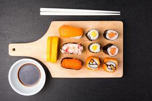 Top view of Sushi set on wooden tray with chopsticks and sauce on black background, Japanese food. photo