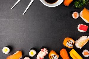 Top view of Sushi set with chopsticks and sauce on black background, Japanese food. Free space for text photo