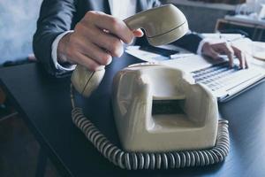 Close up of businessman using telephone while working on the office desk. photo