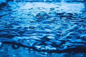 onda azul y burbujas en el fondo de la superficie del agua. foto