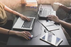 Coworkers working on the same desk, they are using a laptop with tablet, Start up business concept photo