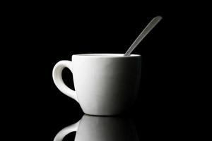 White cup with spoon on black background. photo