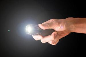 Hand holding flashlight on black background. photo