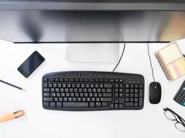 Top view of Desktop computer with office supplies on white background. photo