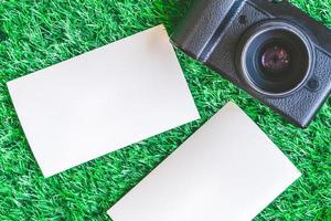 Top view of camera with blank photographs on green grass background. photo