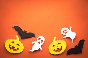 Halloween holiday background with pumpkins, ghosts and bats cut paper on orange background. Free space for text. photo