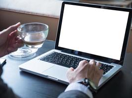 Close up of businessman using a laptop with white screen on the desk. photo