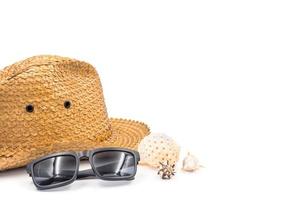 sombrero con gafas de sol y conchas marinas sobre fondo blanco, concepto de vacaciones de verano, espacio libre para texto foto