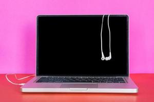 Modern laptop with blank screen and earphones on colorful background. photo