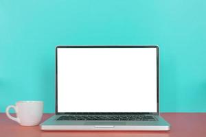 Modern laptop with blank screen, coffee cup on pastel color background. photo