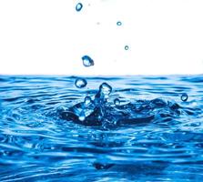 salpicaduras de gotas de agua en la superficie del agua, olas azules y fondo de burbujas. foto