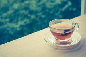 una taza de té en la mesa de madera, bolsita de té en vidrio, fondo natural. tono de época. espacio libre para texto foto