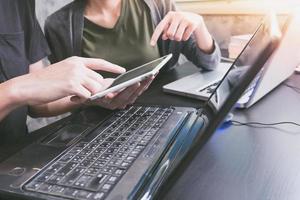 Business partners working together on the same desk, they are using a laptop and tablet, Start up business concept photo