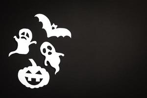 fondo de vacaciones de halloween con calabaza, fantasmas y papel cortado de murciélago sobre fondo negro. espacio libre para texto. foto