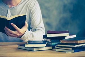 Close up of a man reading a book on the wooden table. Vintage tone photo