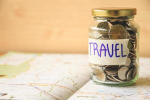 Coins in a glass jar on a map. Saving money for travel concept photo