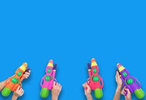 Hands holding gun water toy on blue background. photo