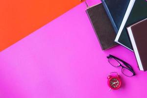 libros de tapa dura con gafas y reloj sobre fondo colorido. espacio libre para texto foto