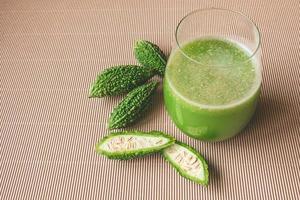 Herbal juice with bitter melon or bitter gourd on wooden background. photo