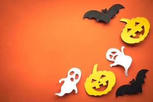 fondo de vacaciones de halloween con calabazas, fantasmas y murciélagos cortan papel sobre fondo naranja. espacio libre para texto. foto