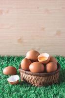 Eggs in wooden basket on green grass. Free space for text photo