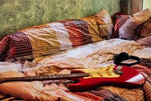 guitarra eléctrica y auriculares en el dormitorio, filtro de grano de películas. foto