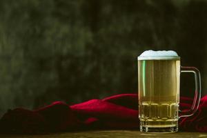 jarra de cerveza con pañuelo rojo en la mesa de madera. espacio libre para texto foto