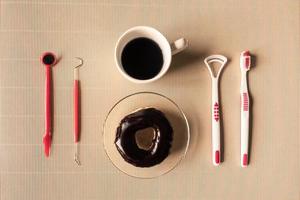 Top view of coffee cup with donut and dental tool equipment on table. photo