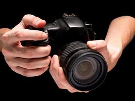 mano masculina sosteniendo una cámara digital sobre un fondo negro. foto