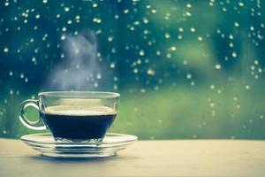 Cup of coffee on the table inside the window, coffee break in the morning with rainy day, relaxing and refreshing concepts. photo