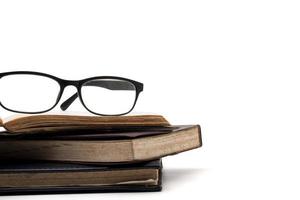 A stack of old books with eyeglasses on a white background. photo