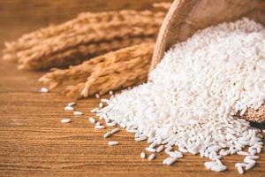 Close up of raw rice in burlap sack on wooden table. photo